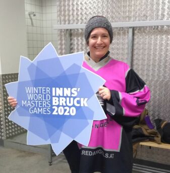 Xpert-Timer Mitarbeiterin hält Schild mit Winter World Master Games hoch